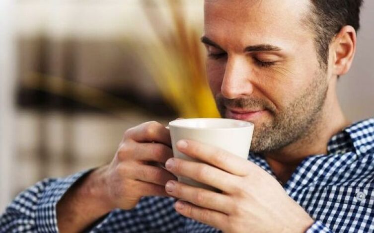 Egy férfi iszik egy ital tűzfű teát, hogy növelje a potenciát
